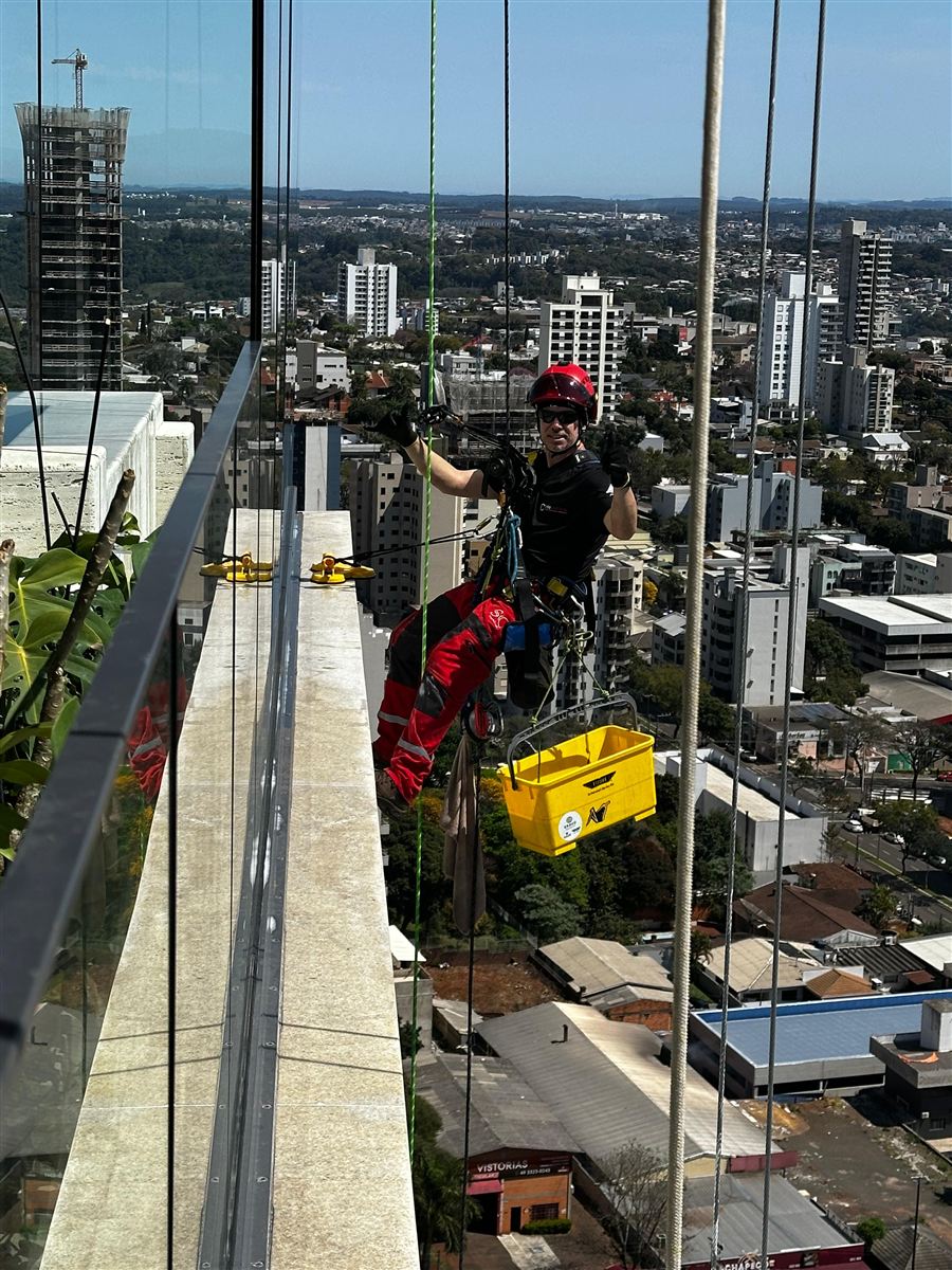Limpeza de fachada envidraçada em prédio alto com acesso por cordas