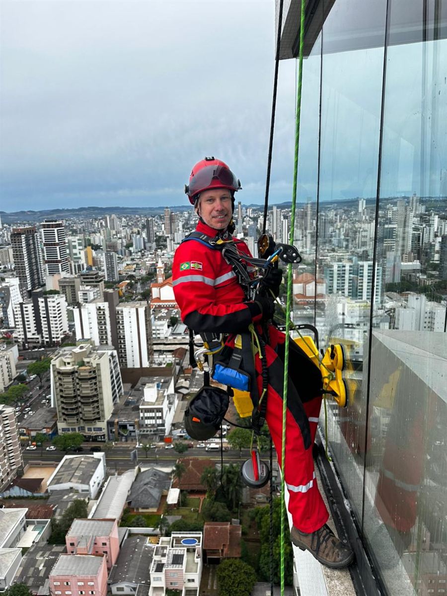 Profissional da PreVertical em acesso por cordas na fachada de um prédio, com a cidade ao fundo